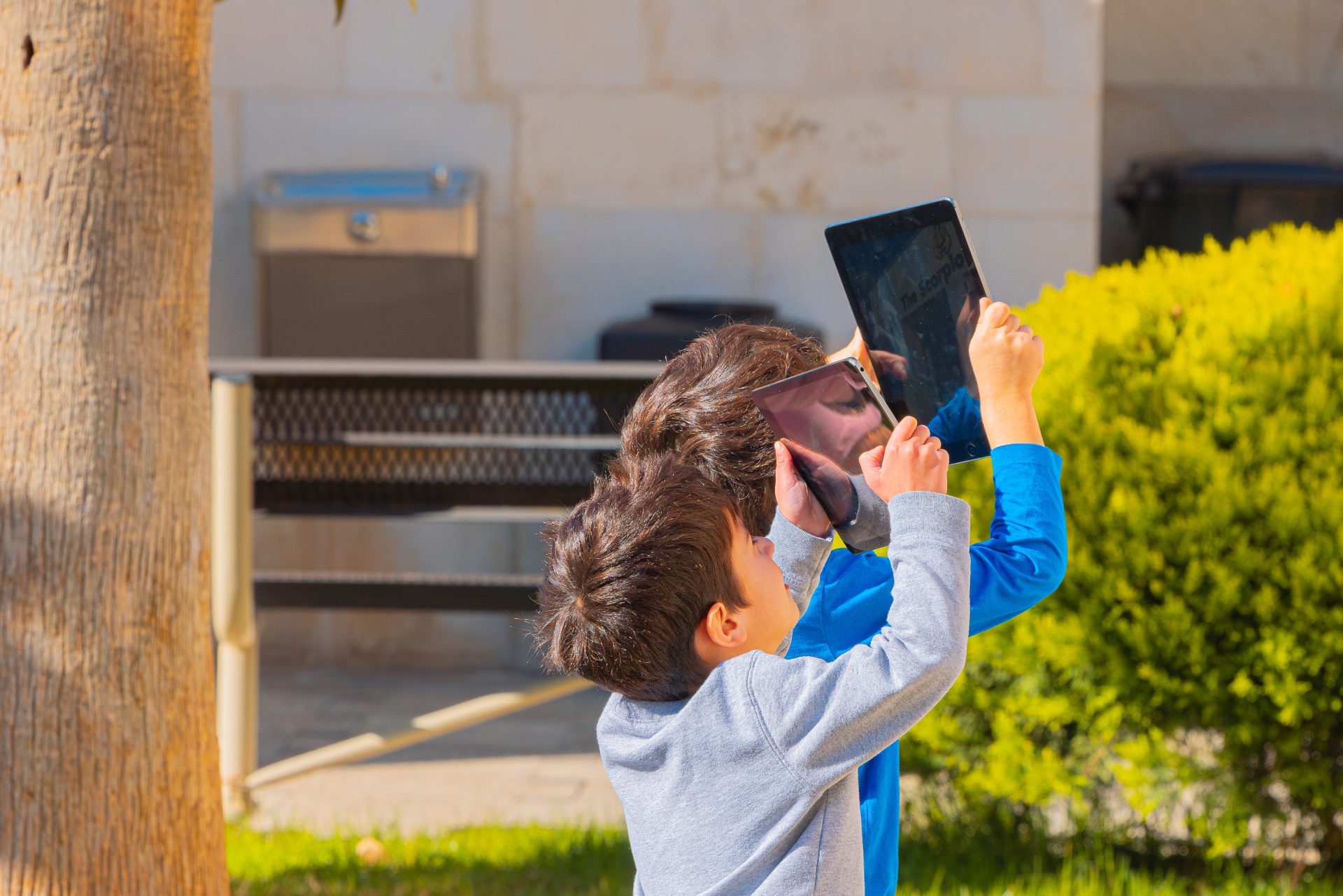 Two boys happily holding iPads while enjoying their time outdoors.